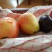 Auf dem Foto sieht man einen Apfel, eine Birne, eine Pflaume und eine Nektarine auf einem Küchentuch